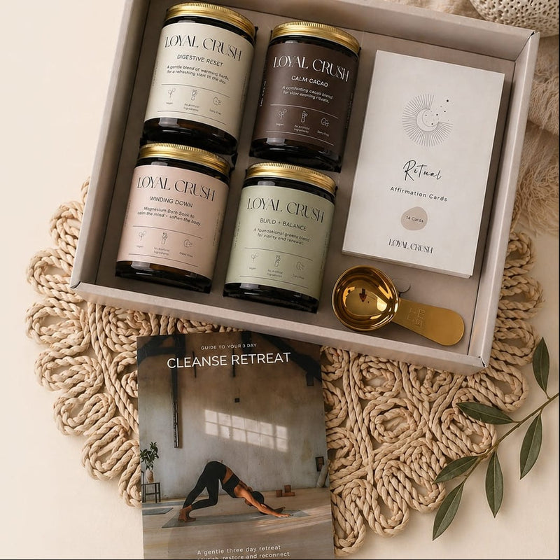 Set of healthy powders and a book titled 'Cleanse Retreat' in a box on a textured surface.