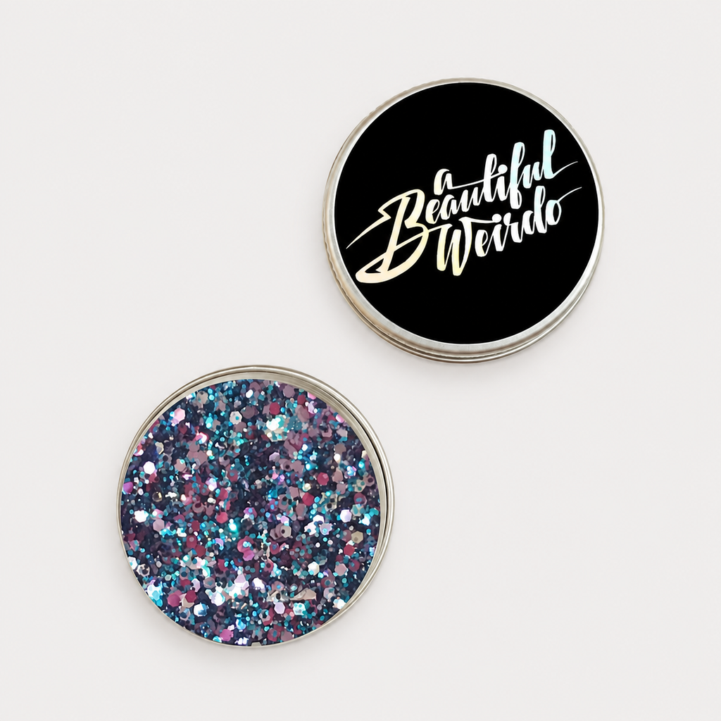 A Beautiful Weirdo Oil Slick Eco Glitter — tin and lid on pale grey